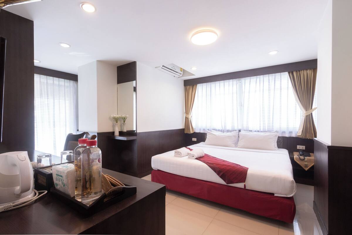 A hotel room with a bed, bedside table, and a desk with a telephone and toiletries.
