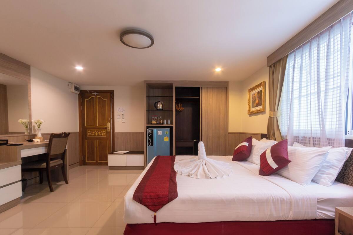 A hotel room with a bed, a desk, a wardrobe, and a minibar.