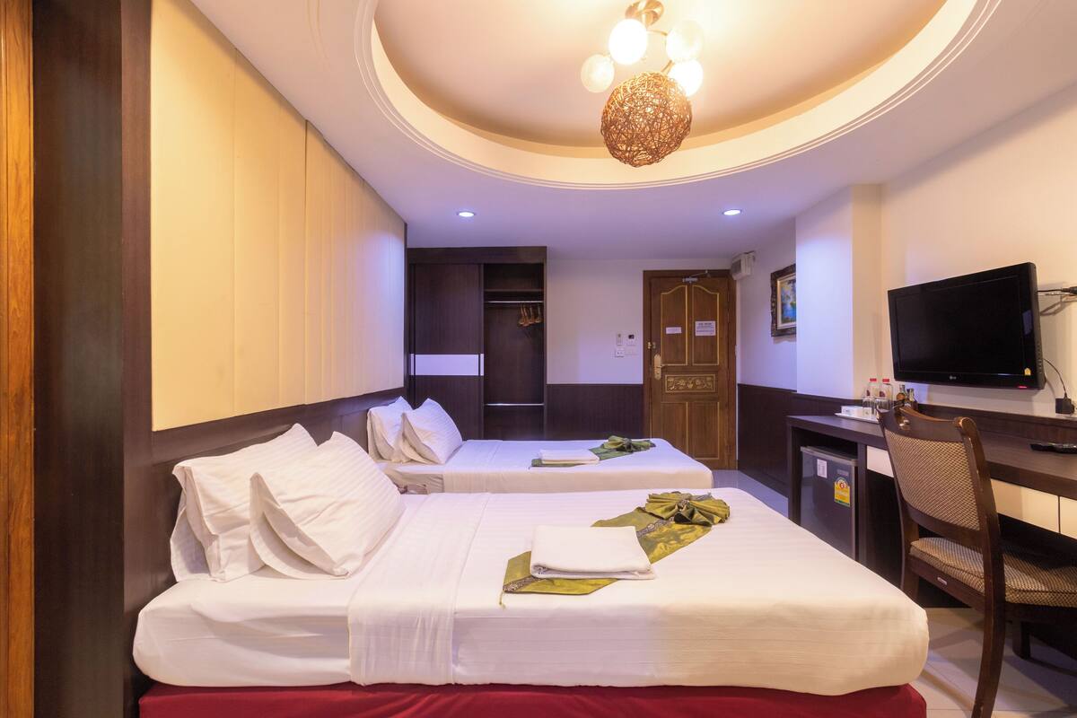 A hotel room with two beds, a desk, a television, and a wardrobe.
