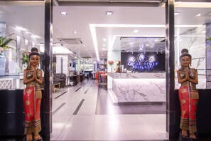Una zona de recepción con mostrador de mármol y dos estatuas de mujeres con atuendo tradicional.