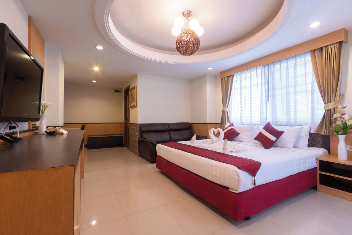 A modern hotel room with a large bed, a desk, and a television.