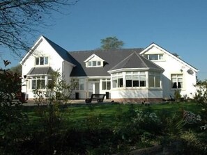 A two-story house with a large front lawn, a conservatory, and a detached garage. - Hazelwood Guest House (Bridgend)