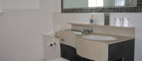 A bathroom with a toilet, sink, and mirror.