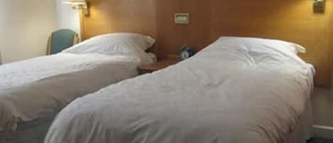Et hotelværelse med to senge, et træhovedgærde og to væglamper.