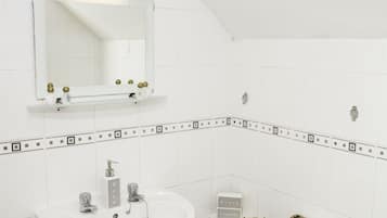 A bathroom with a white sink, a mirror, and a towel basket.