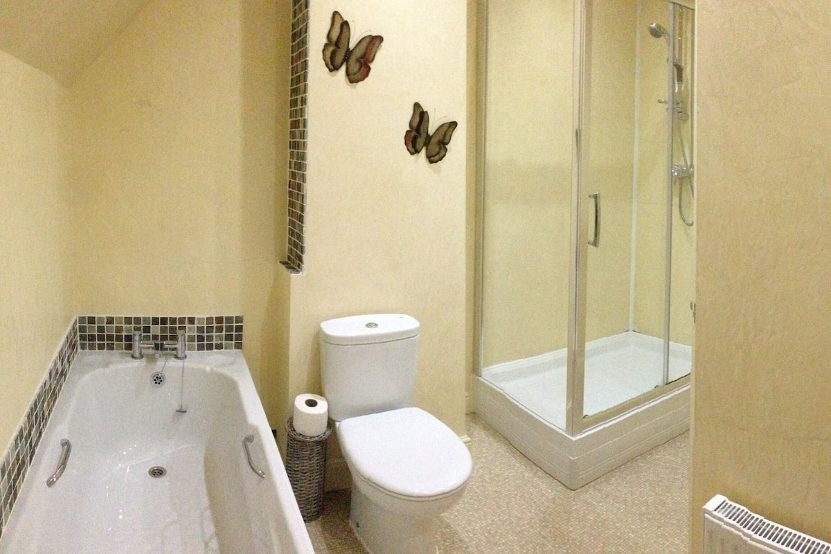 A bathroom with a bathtub, toilet, and glass shower enclosure.