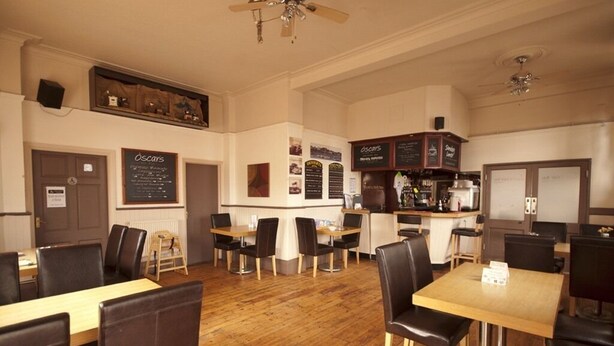 Un restaurante espacioso con suelo de madera, varias mesas y sillas, y un ventilador de techo.