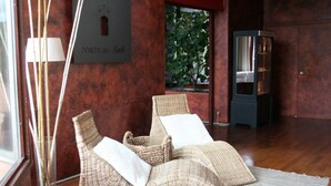 A room with two wicker lounge chairs, a floor lamp, a cabinet, and a window with a view of greenery. - La Chaumette Porte des Suds (Privas)