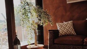 A cozy living area with a wicker sofa, a potted plant, and a lantern. - La Chaumette Porte des Suds (Privas)