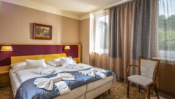 A hotel room with a large bed, two bedside lamps, a chair, and a painting on the wall.