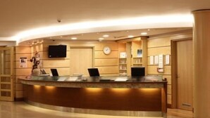 A reception desk with a curved design, a clock, and a television mounted on the wall.