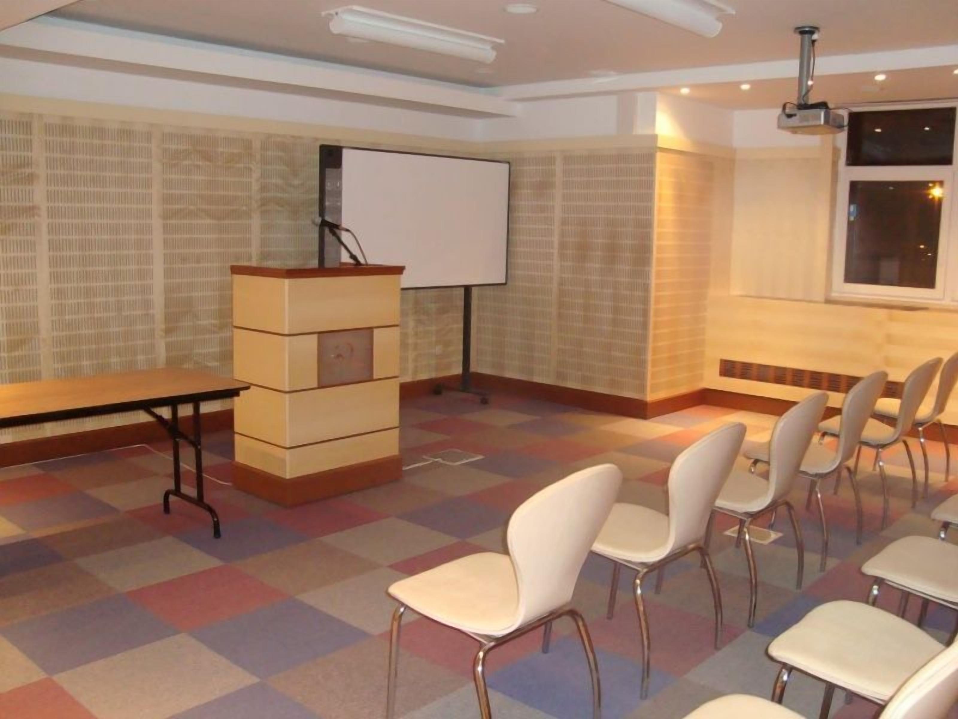 A conference room with a whiteboard, a podium, and rows of chairs.