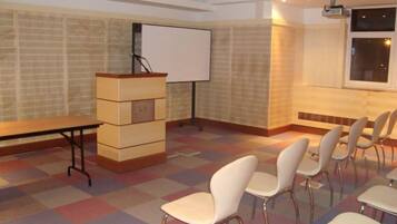 A conference room with a whiteboard, a podium, and rows of chairs.