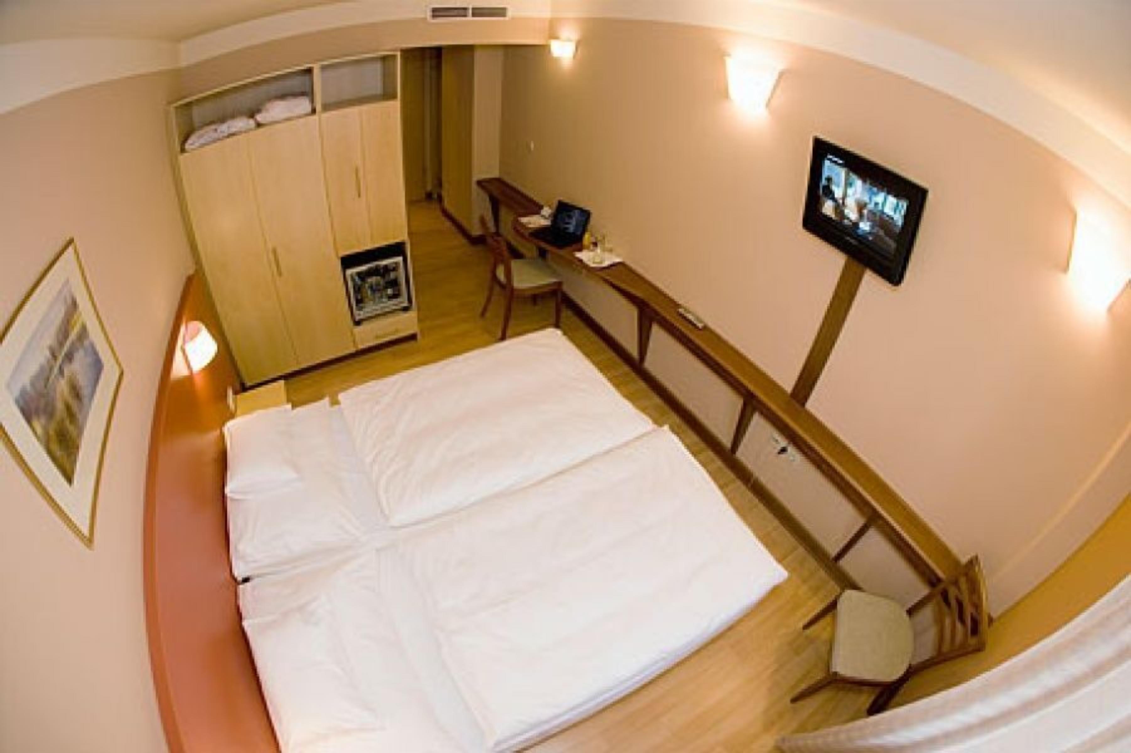 Ett hotellrum med en säng, ett skrivbord, en tv och en garderob.