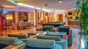 A hotel lobby with a pool table, comfortable seating, and a reception area.