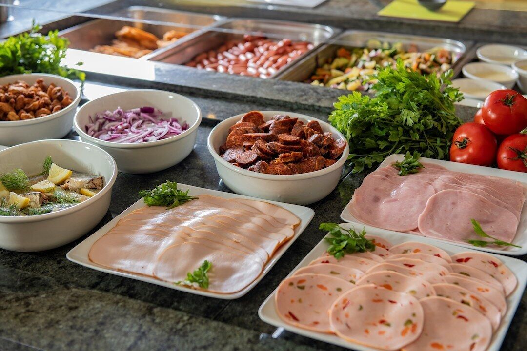 Un buffet proposant une variété de plats, notamment des viandes en tranches, des légumes et des accompagnements.