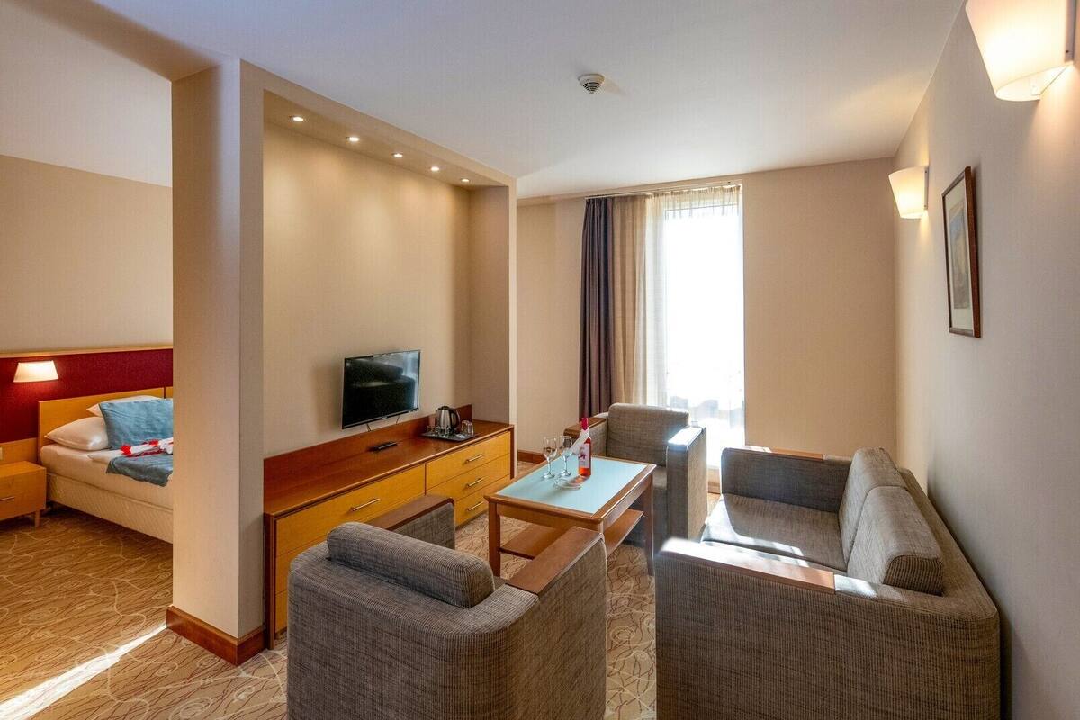 Ein Hotelzimmer mit einem Bett, einem Fernseher, einem Schreibtisch mit Stuhl und einer Couch.