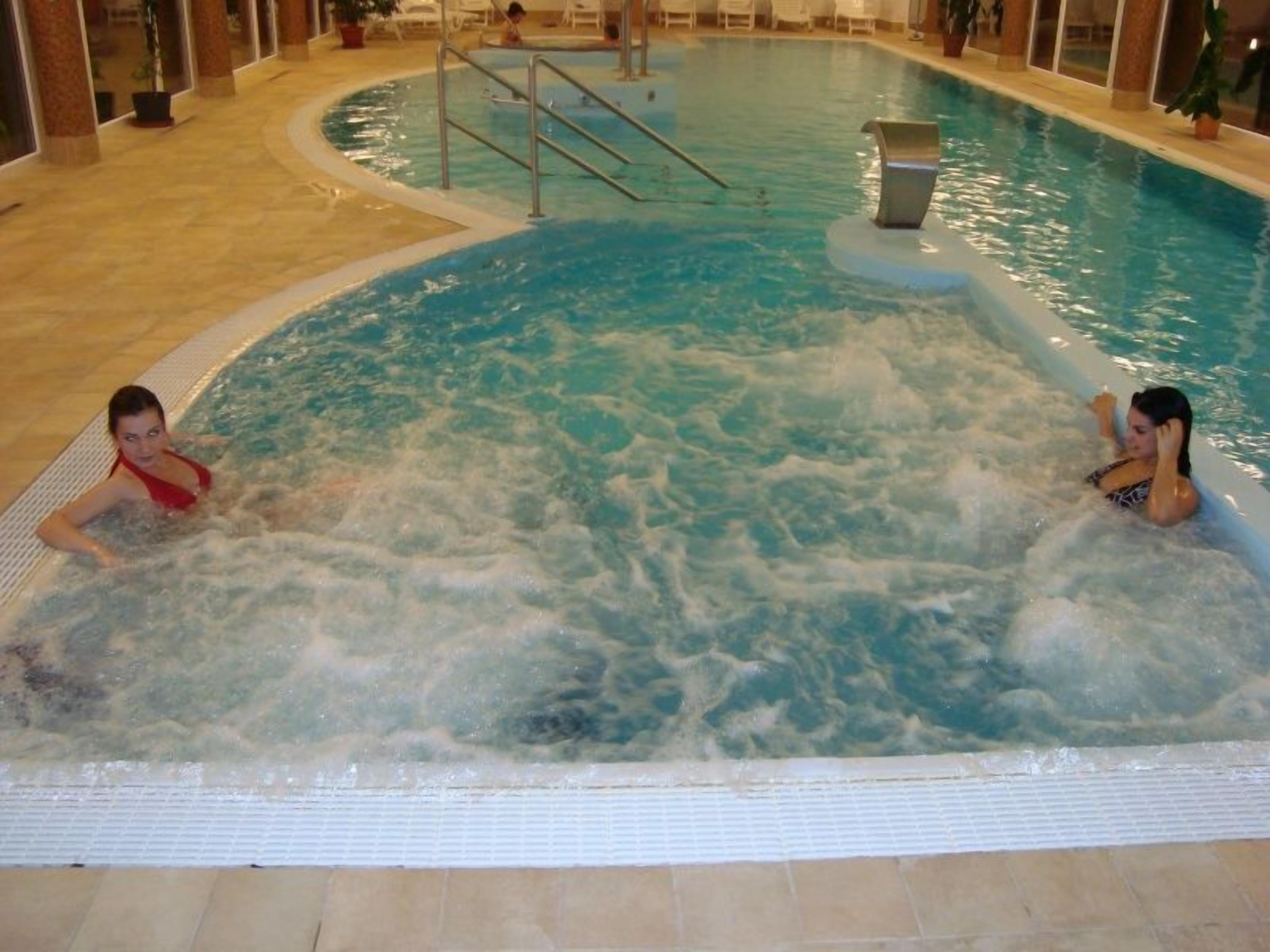An indoor swimming pool with two people in the water.