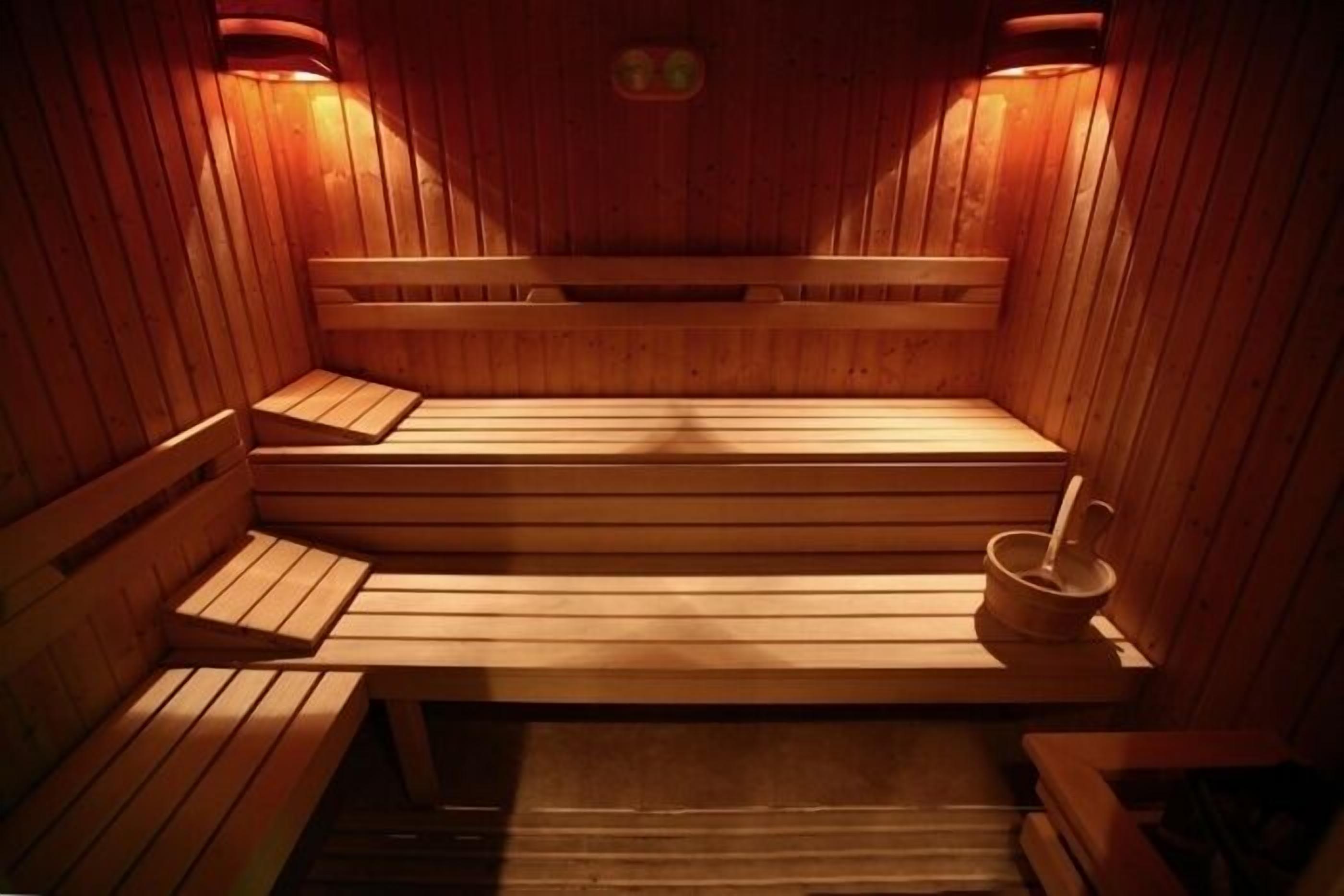 Een houten sauna met banken en een kleintje tafeltje met een beker en een lepel.