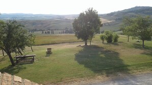 A grassy field with a picnic table and a brick wall. - Agriturismo Barbi (Pienza)
