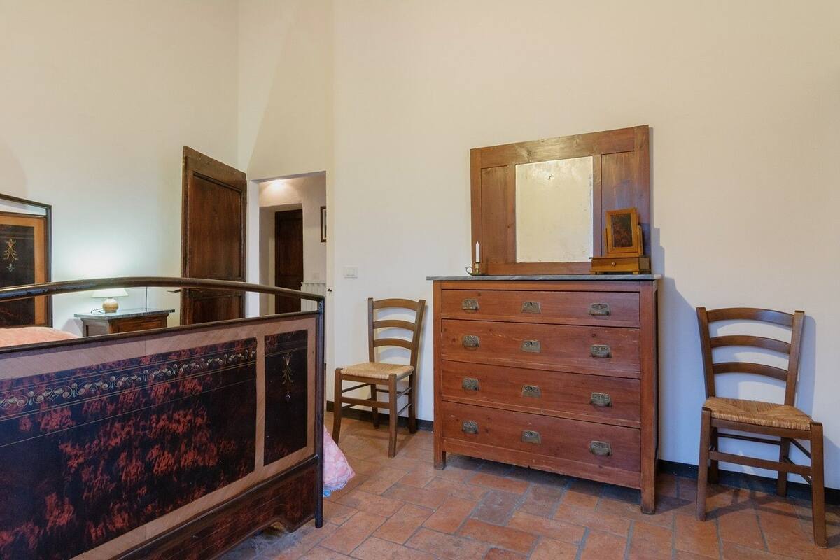Un dormitorio con una cama, un tocador, dos sillas y un espejo.