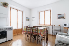 A kitchen with a stove, dining table with chairs, and a radiator. - Agriturismo Barbi (Pienza)