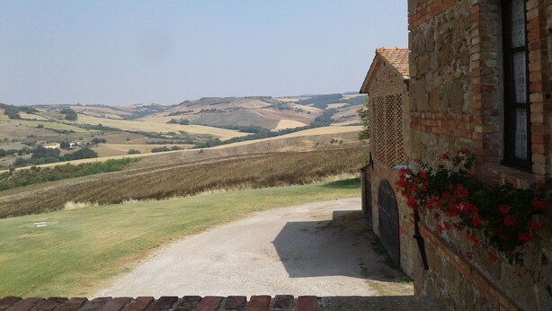 A stone building with a brick pathway leading to a grassy field. - Agriturismo Barbi (Pienza)