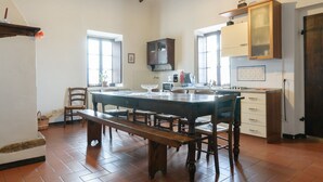 A spacious kitchen with a large island, wooden cabinets, and a dining area with a bench. - Agriturismo Barbi (Pienza)