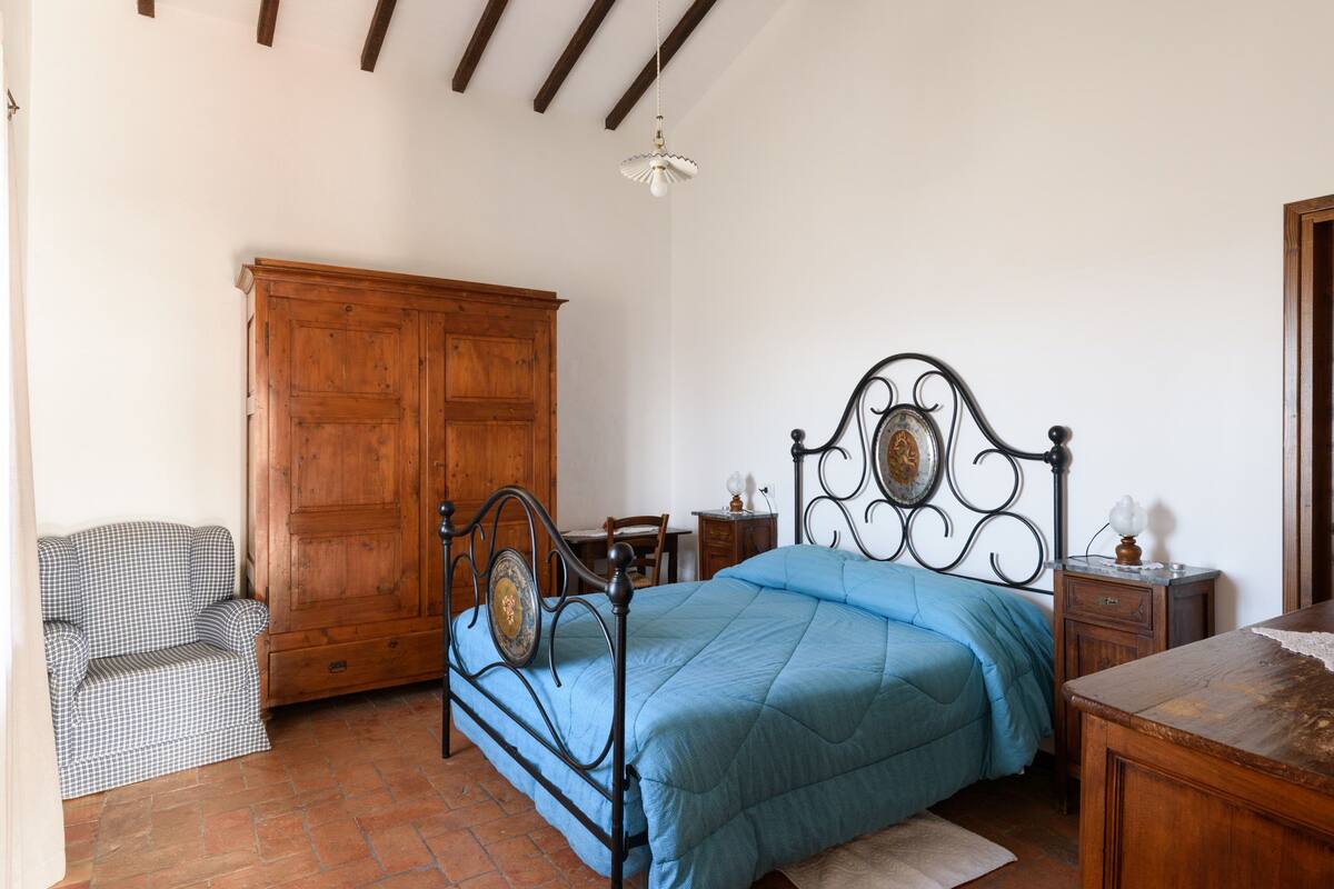 Un dormitorio con una cama, armario de madera y una silla.