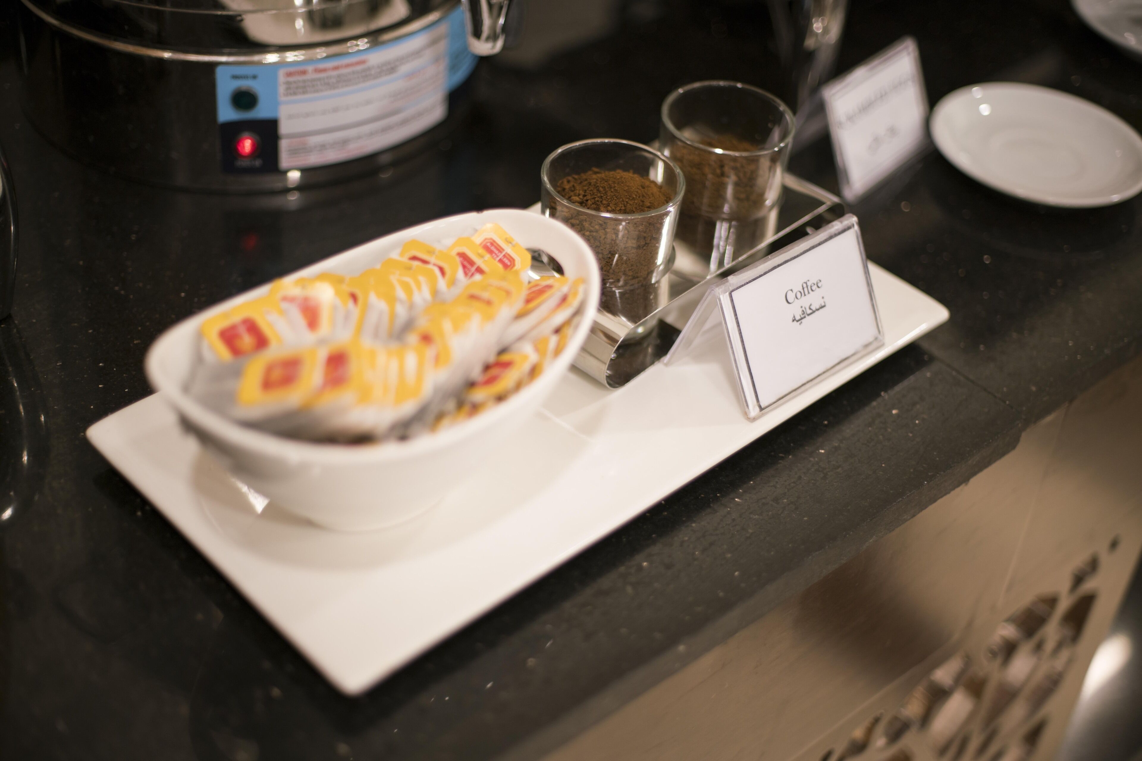 Un espace dédié au café, équipé d’une machine à café, de tasses et d’un panneau indiquant le service de café.