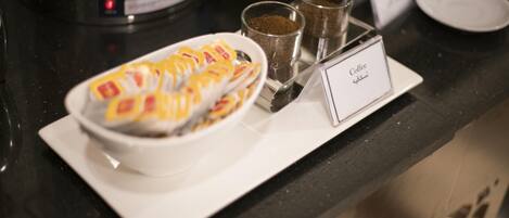 Un espace dédié au café, équipé d’une machine à café, de tasses et d’un panneau indiquant le service de café.