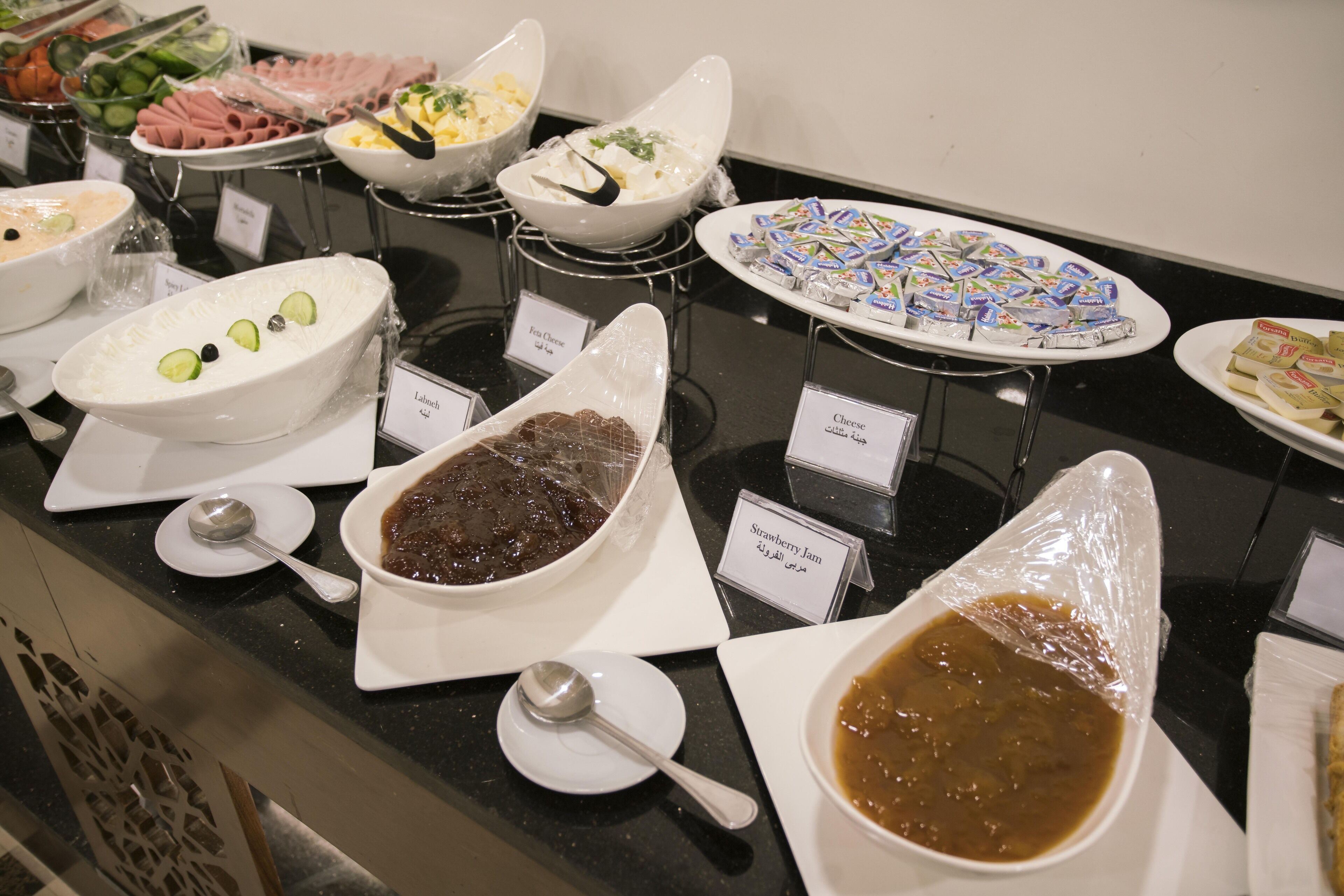 A buffet with various food items including a bowl of chocolate dessert, a bowl of fruit salad, and several dishes of cheese and other spreads.