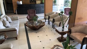 A lobby with a reception desk, a staircase, and seating areas with sofas and armchairs. - Dweik Hotel 2 (Aqaba)