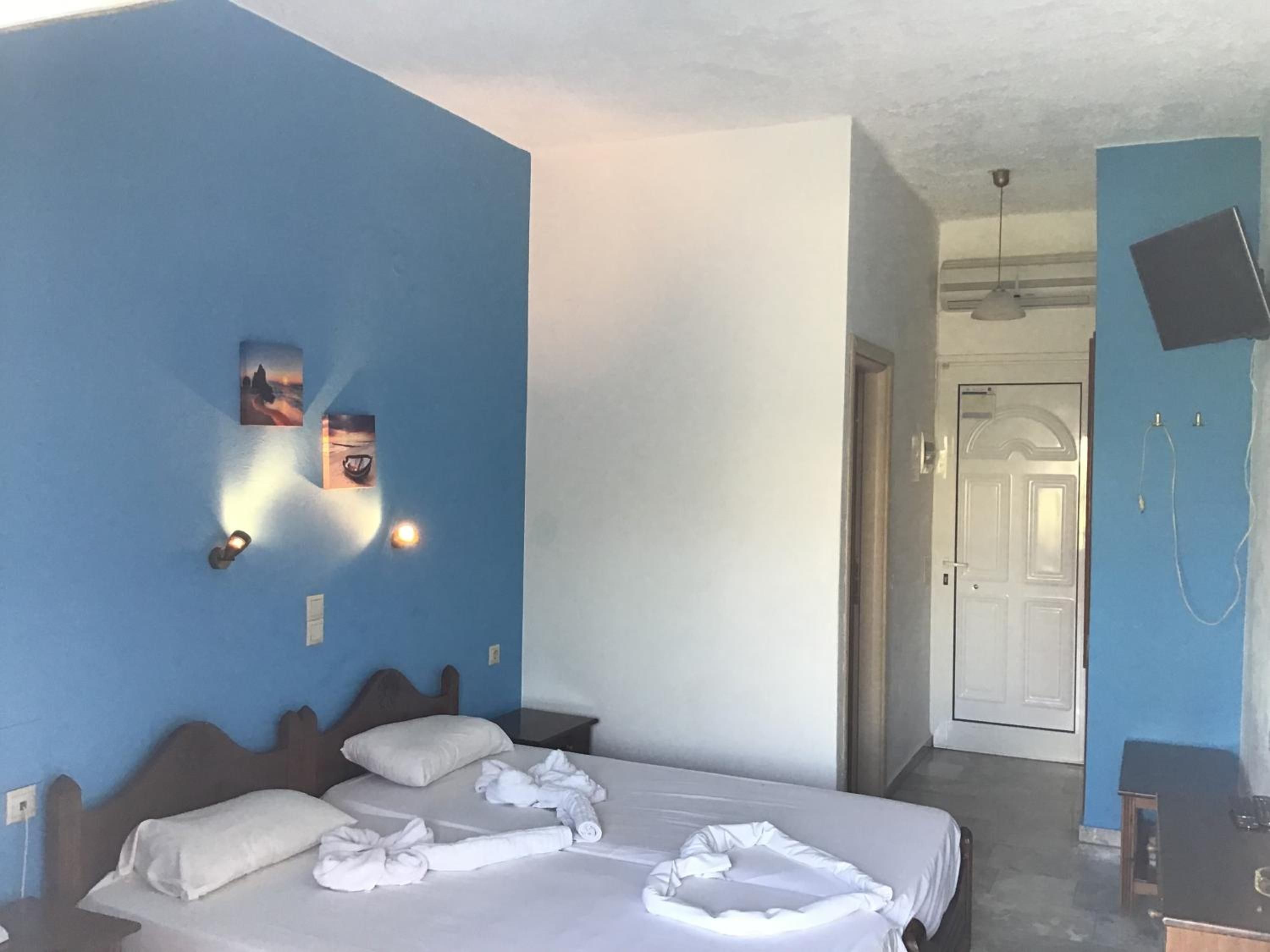 A hotel room with a bed, two wall-mounted lights, a TV, and a shower area.