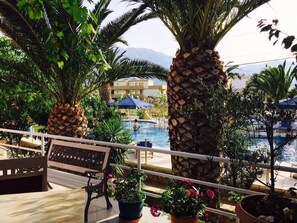 A poolside area with palm trees, a bench, and potted plants. - Anatoli Beach (Apokoronas)