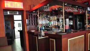 En hotelbar med et receptionsområde, hylder med spiritusflasker og et Coca-Cola køleskab.