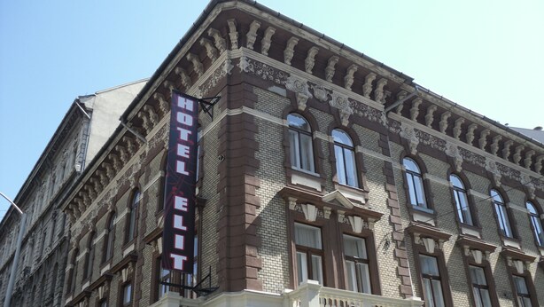 En historisk bygning med et tydeligt skilt, der siger "HOTEL EDIT", store vinduer og detaljeret murværk.