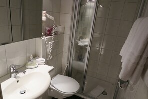 A bathroom with a sink, toilet, and glass shower enclosure.