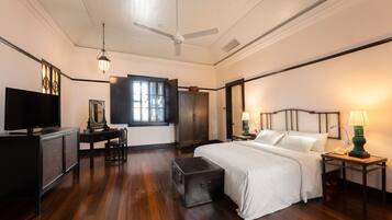 A hotel room with a bed, a desk with a television, a wardrobe, and a window.
