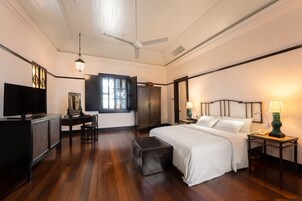 A hotel room with a bed, a desk with a television, a wardrobe, and a window.
