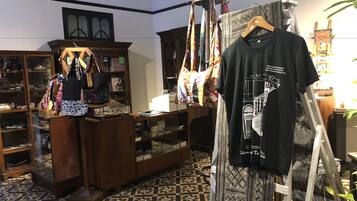 Una boutique exhibe una variedad de bolsos, un maniquí viste una camiseta negra y el suelo presenta un estampado.