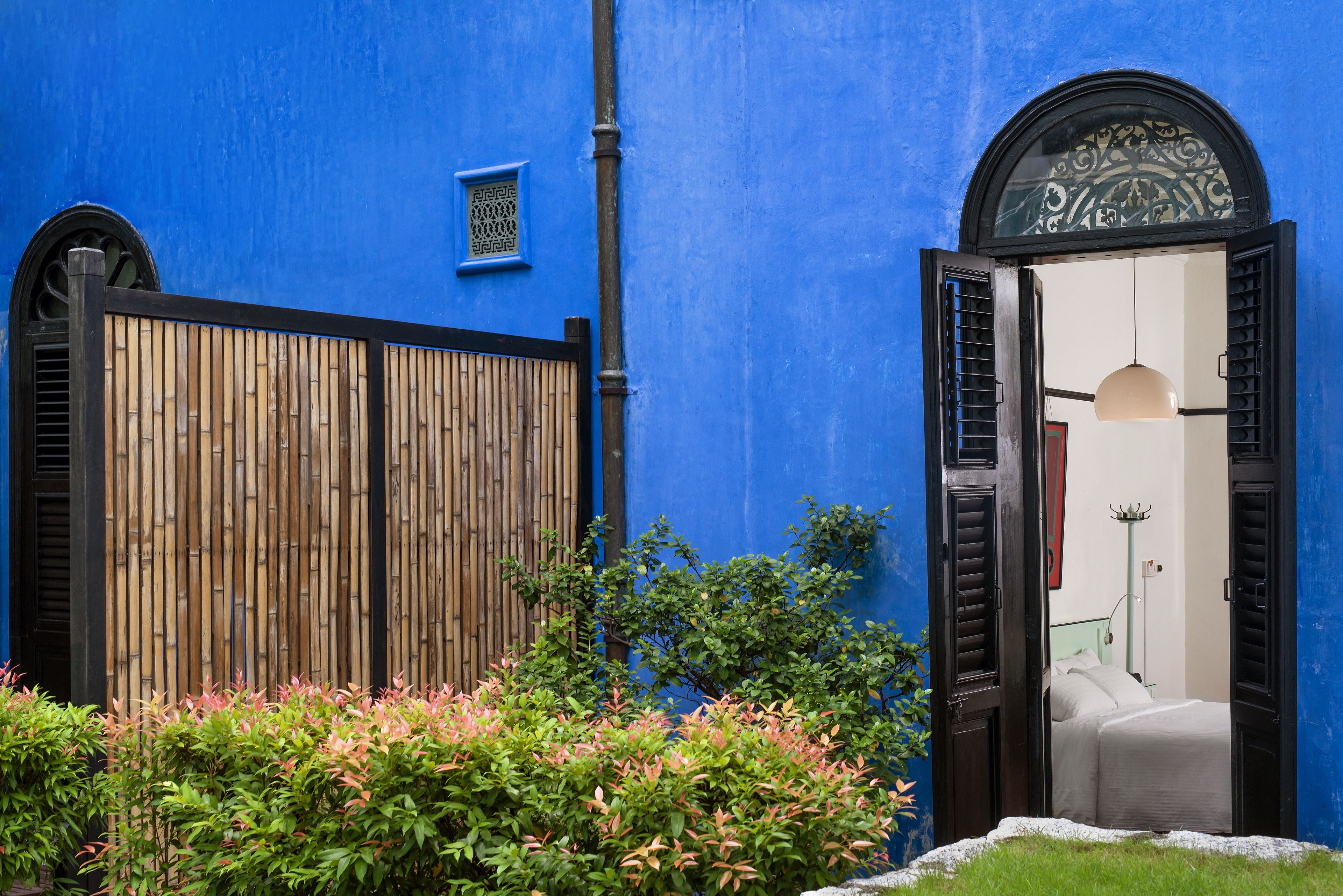 A blue building with a wooden fence, a bed, and a nightstand.