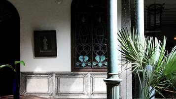 A room with a patterned floor, a table with chairs, a potted plant, and a decorative column.