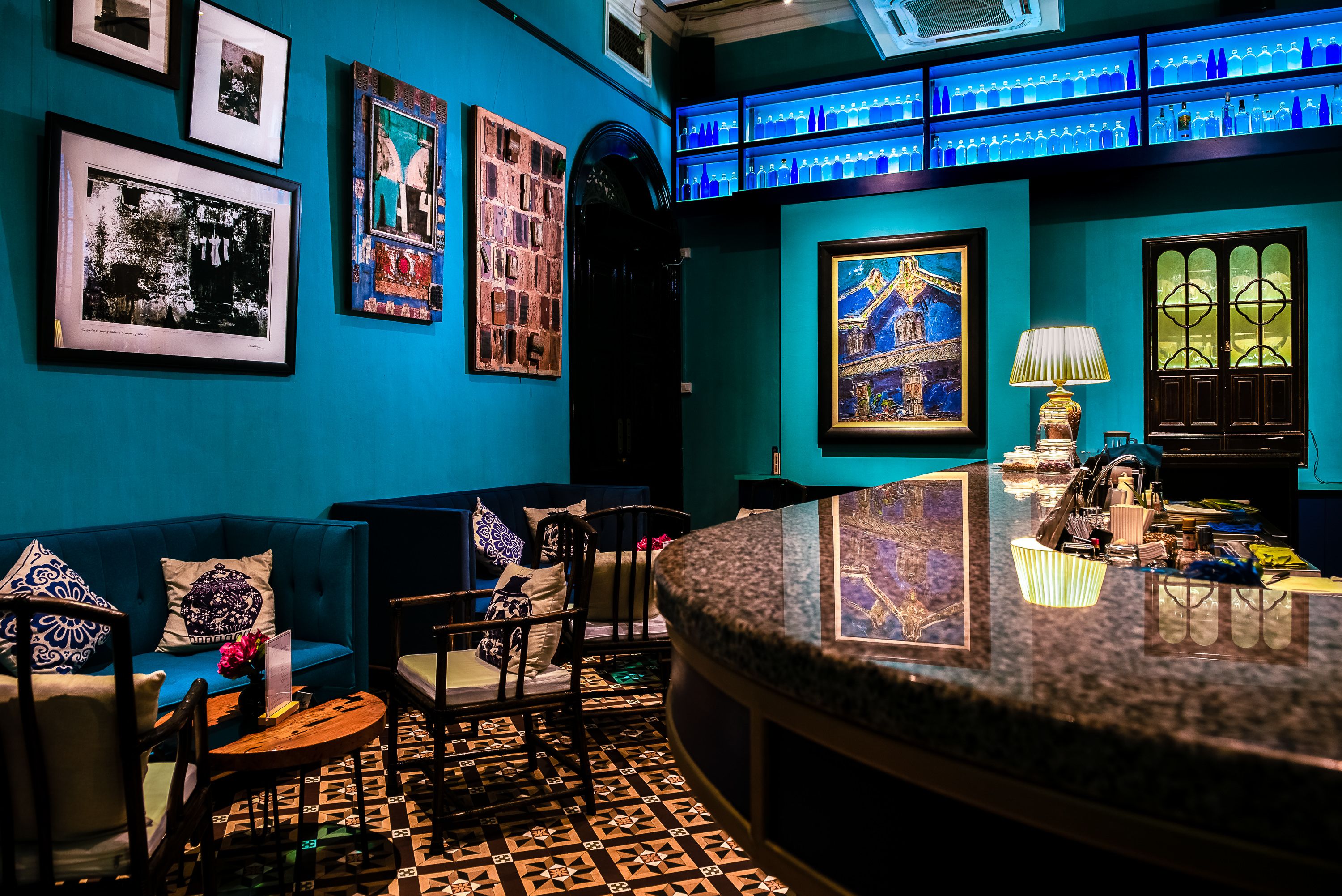 A bar area with a blue wall, framed pictures, and a patterned floor.