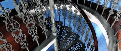 A spiral staircase with ornate metal railings and a wooden handrail.