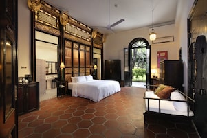 Une chambre spacieuse avec un grand lit, un canapé et une vue sur le jardin grâce à une porte ouverte.