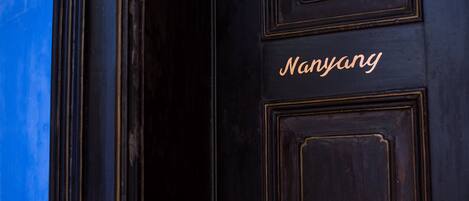 A dark wooden door with the name "Nanyang" in gold lettering.