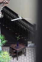 A staircase with ornate balusters, a white ceiling fan, and a table with a vase.