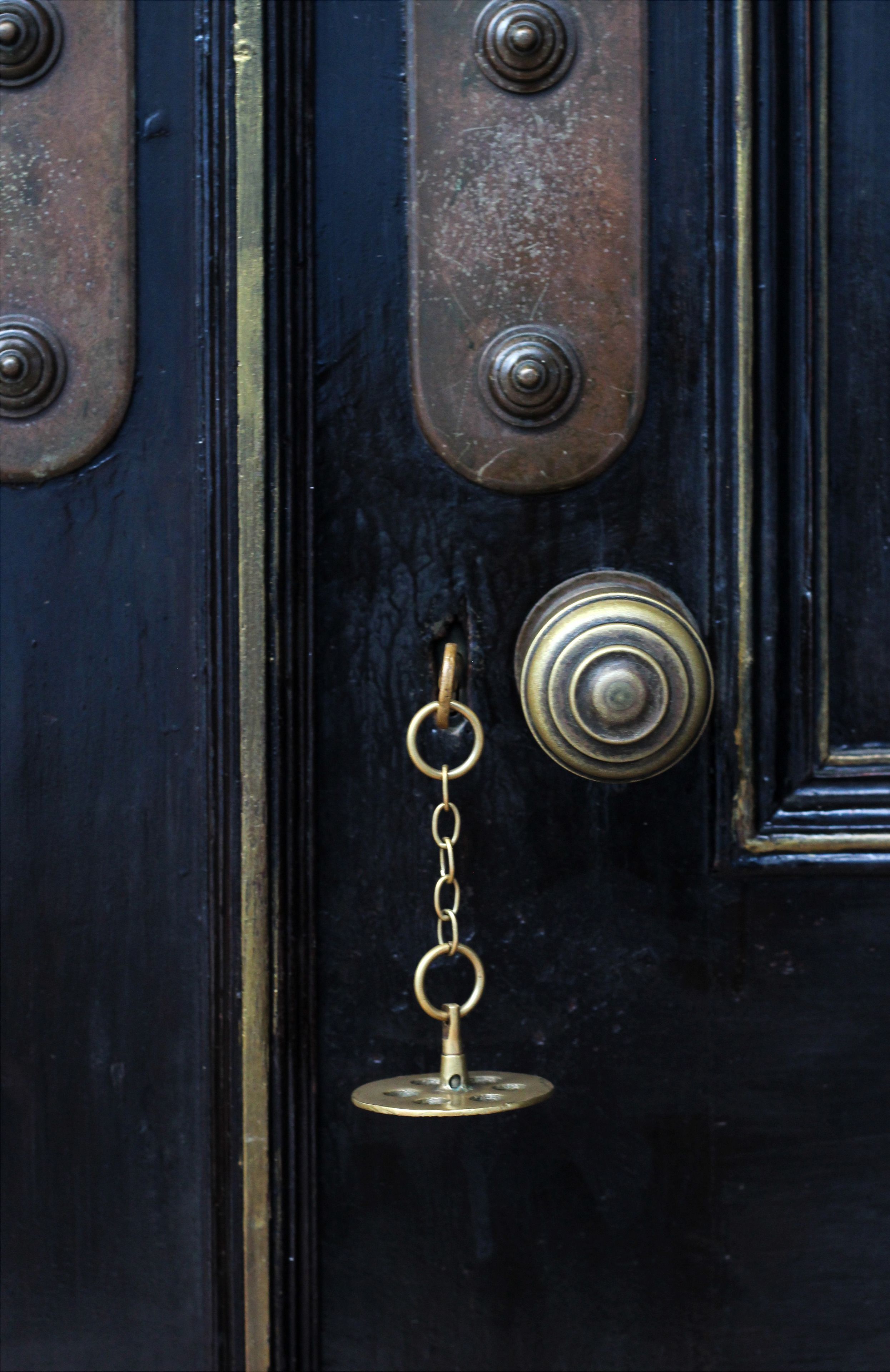 A close-up of a black door with a brass doorknob and a keychain.