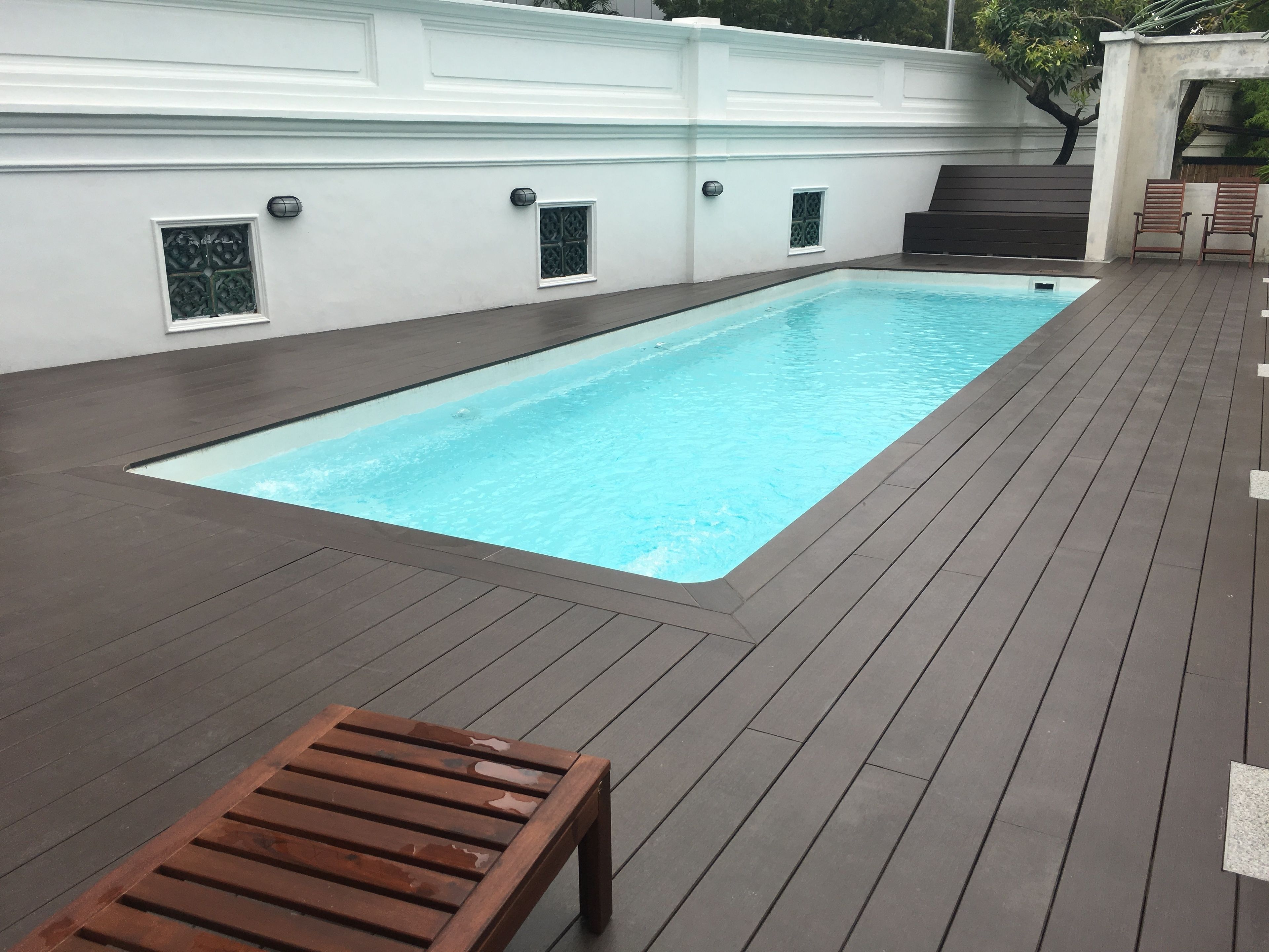 A rectangular swimming pool with a wooden deck surrounding it.